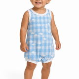 A smiling toddler standing barefoot against a white studio background, wearing a sleeveless light blue and white gingham romper with small white cloud motifs and white trim.