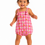 A smiling toddler girl wearing a pink and white gingham bubble romper with a daisy print, standing against a plain white background.